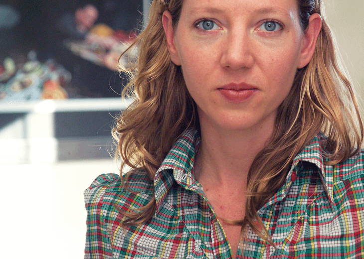 Photo of author Maggie Nelson in a plaid shirt, starring straight at the camera