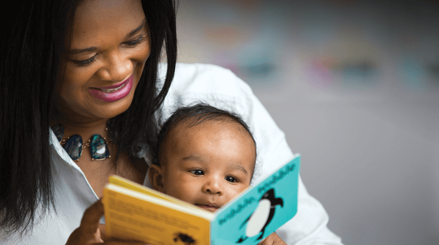 mother reading a board book to a young baby