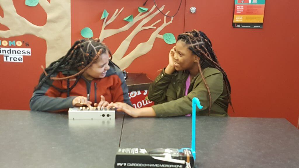 Two teens laughing while playing a game.