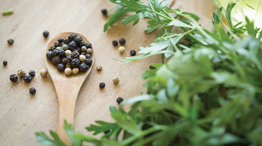 Fresh herbs and a wooden spoon full of peppercorns.