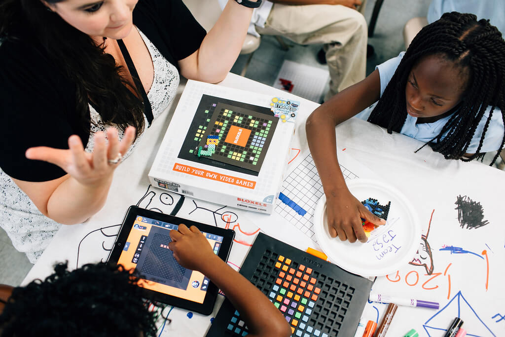 Kids sit around a table learning about building video games with Bloxels.