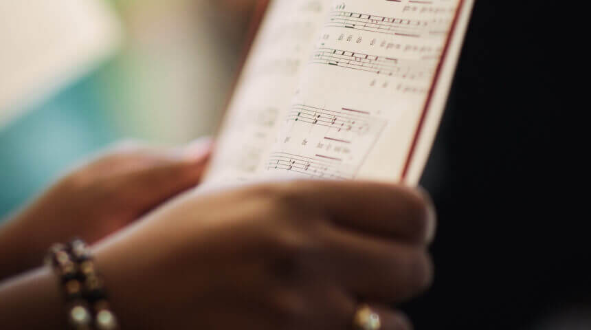 A close-up photo of an open sheet music book being held by two hands