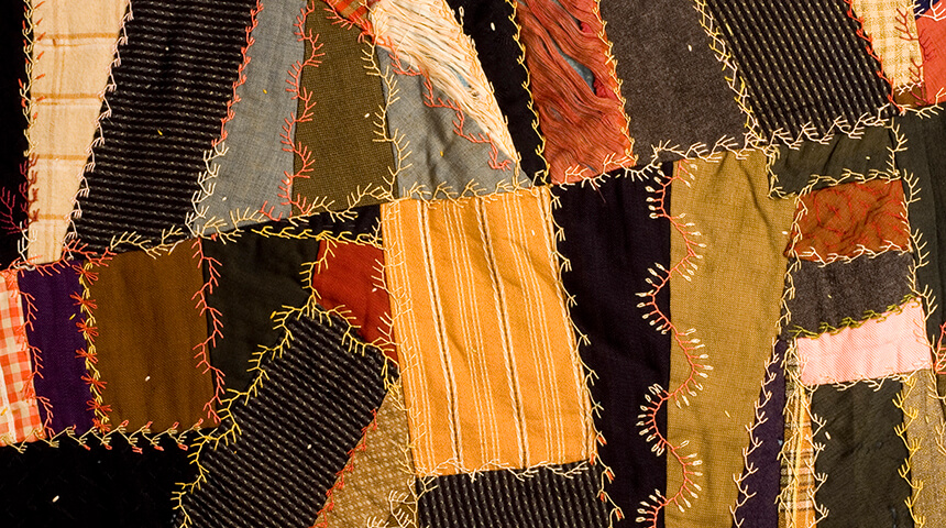 Asymmetrical patchwork antique quilt with hand embroidery.