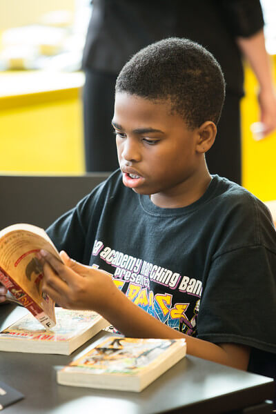 A teen flips through a book of manga.