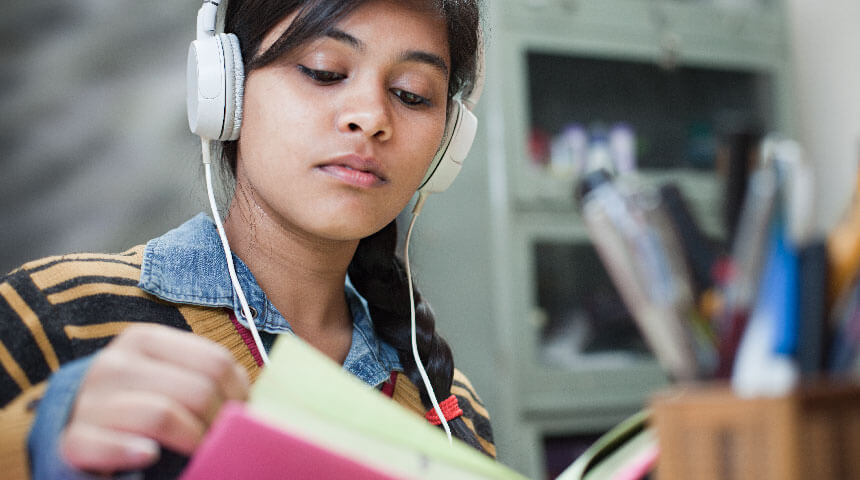 Teen wearing headphones and reading a book