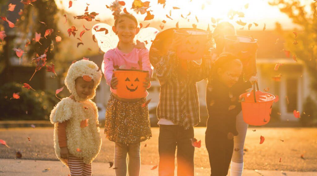 Five young children dressed in Halloween costumes going trick or treating.