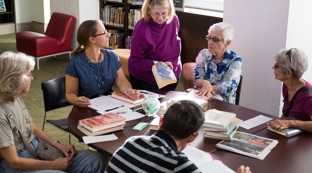 Group of adults around a table of books.