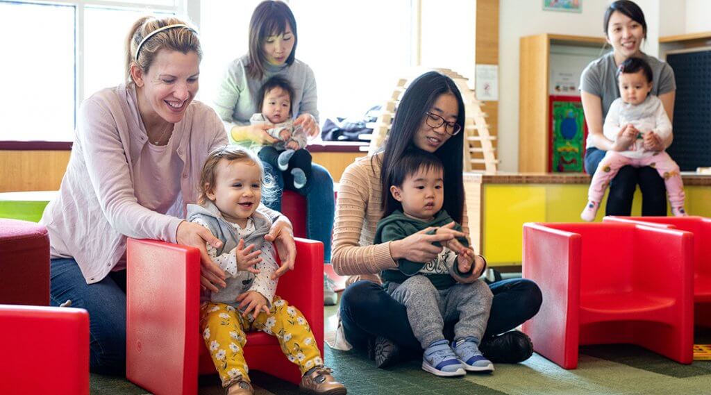 Four babies and their caregivers participate during a storytime.