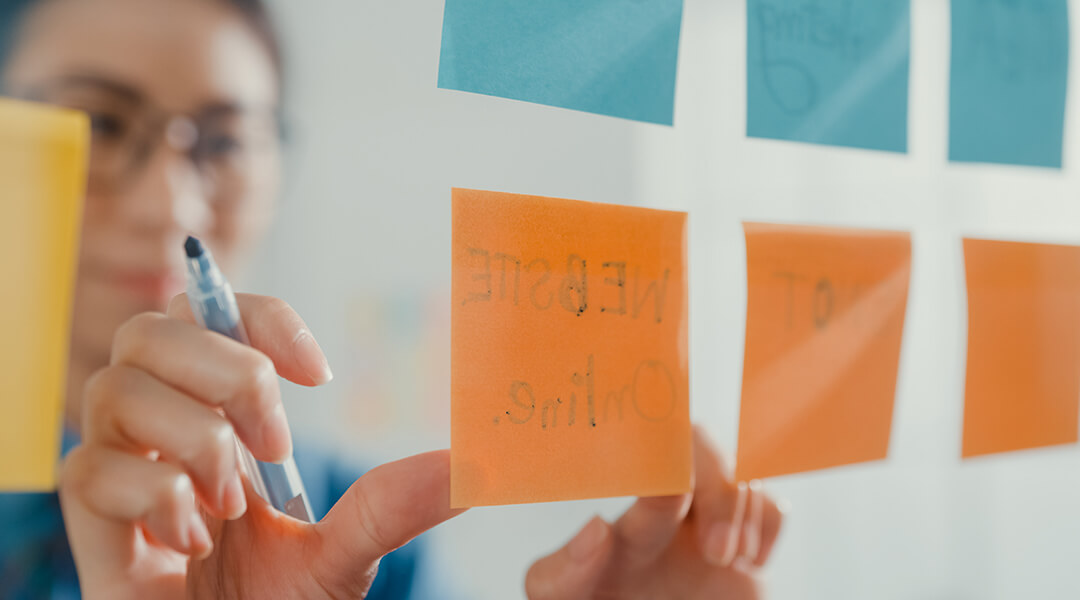 Young businesswoman write on colorful sticky notes develop project in creative office.