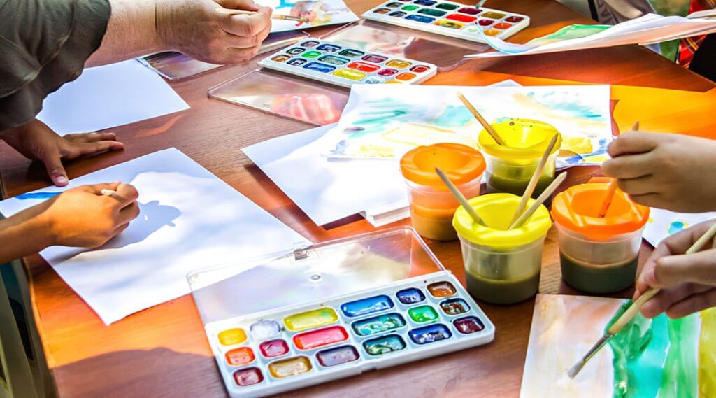 Close-up of shared watercolor supplies on a tabletop.