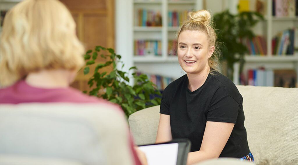 A young adult is interviewed in an office.