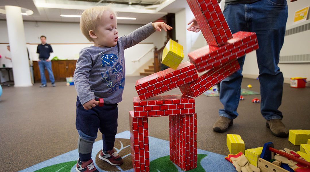 A toddler plays with cardboard building bricks.