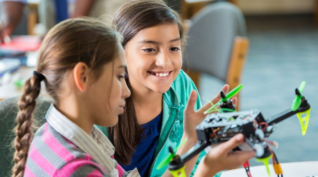 Two students examine a small robotic drone they have built together.