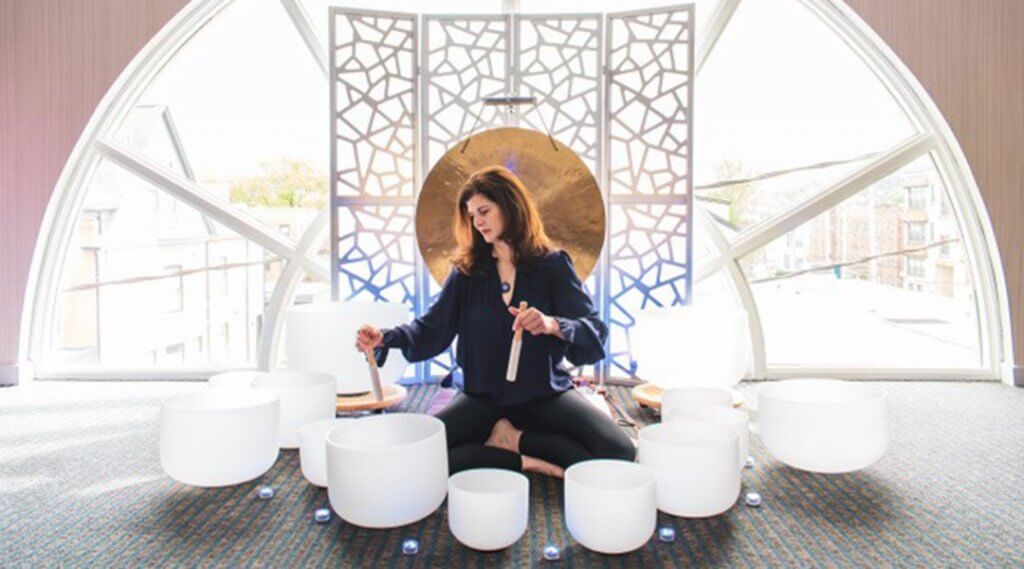 Monique Mead performing a sound bath with large white bowls.