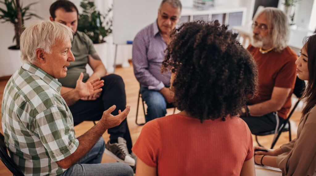 Group of adults sitting in a circle in conversation