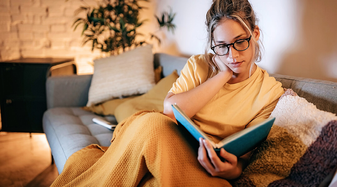 Woman on a couch engrossed in a book.