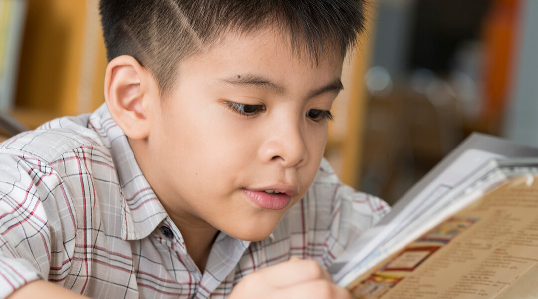 Child, about 7 years old, engrossed in a book.