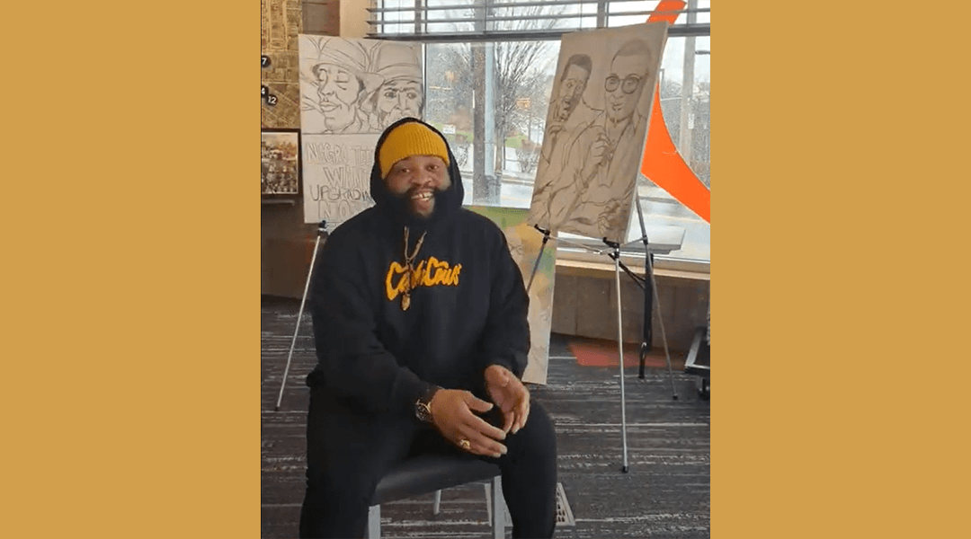 Artist Lee Price smiling in front of his artwork in CLP Hill District.
