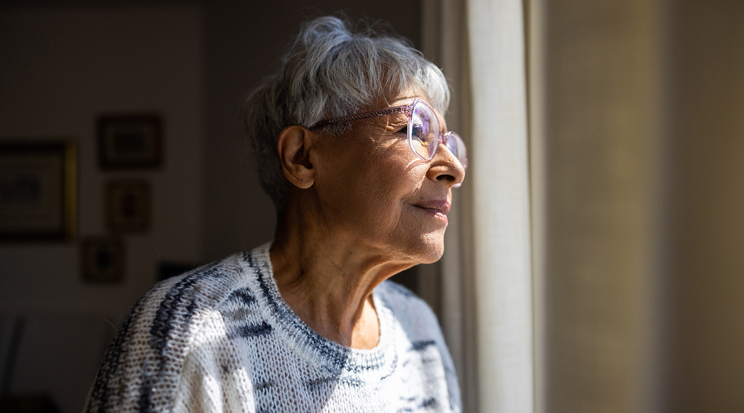 A senior adult looks out of a window.