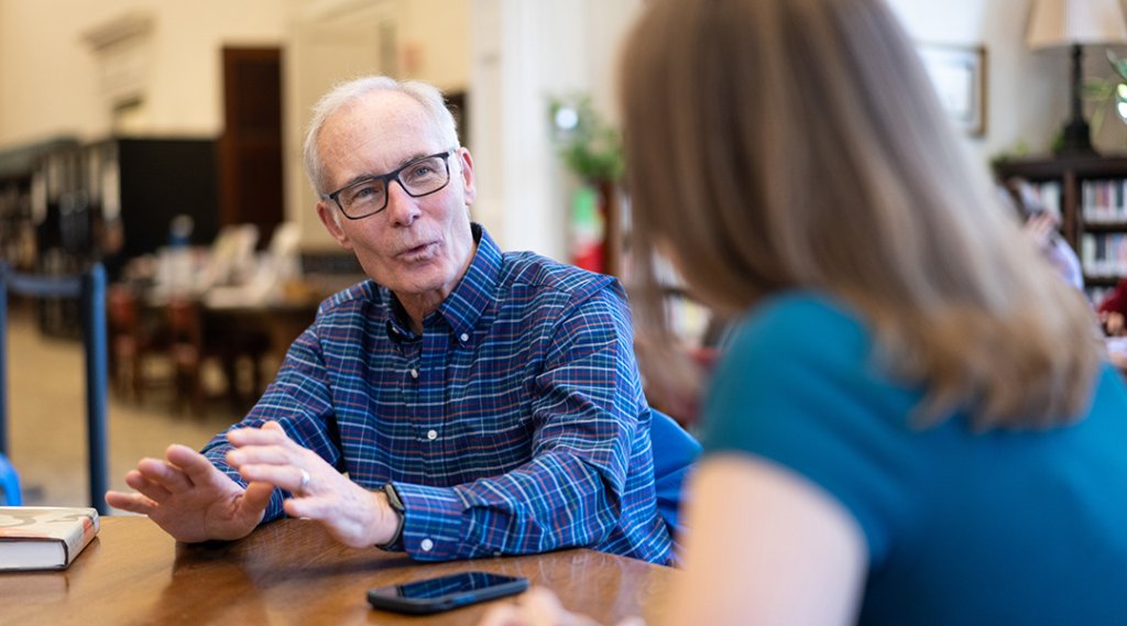 A mature adult talks with a librarian.