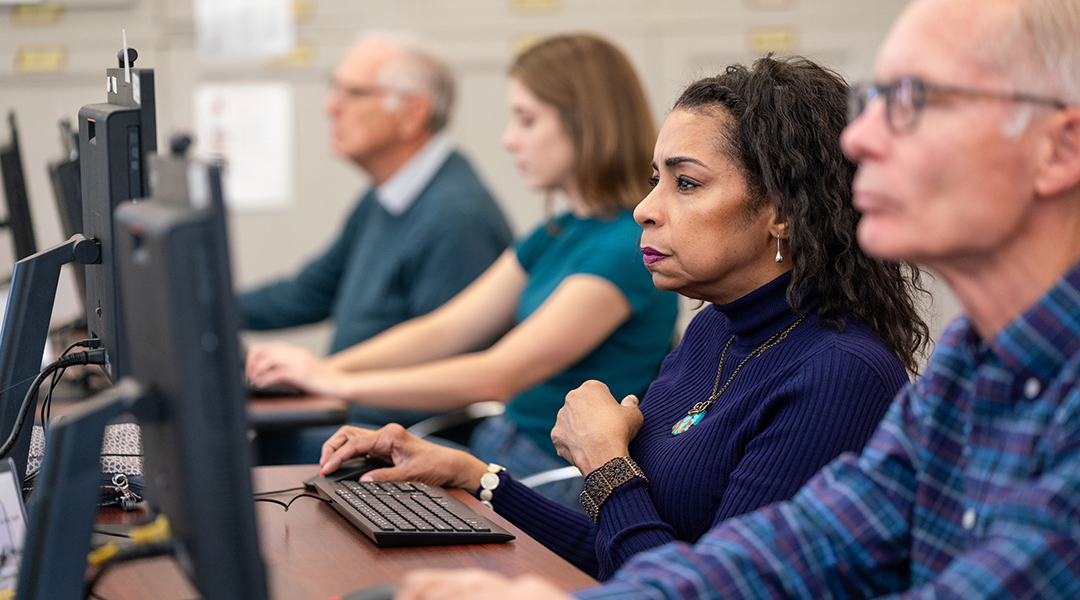 Adults of varying ages use the public computers in the library.