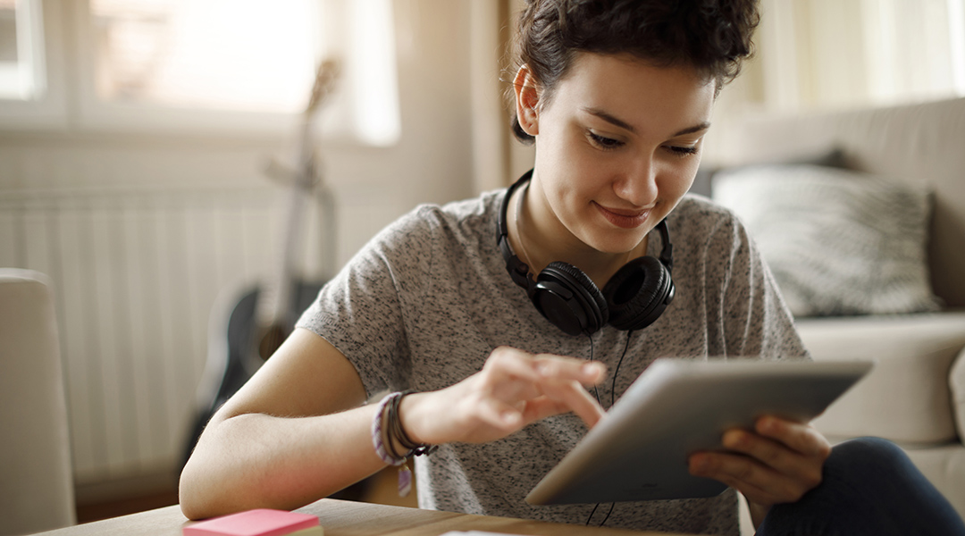 A young adult uses a tablet at home.