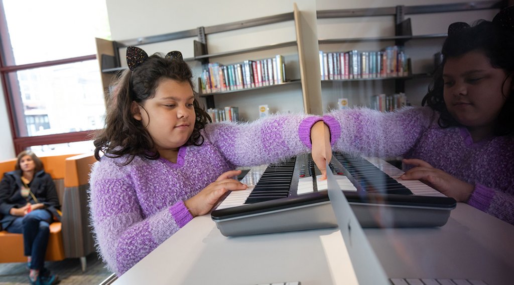 A child plays with an electronic keyboard in the library.