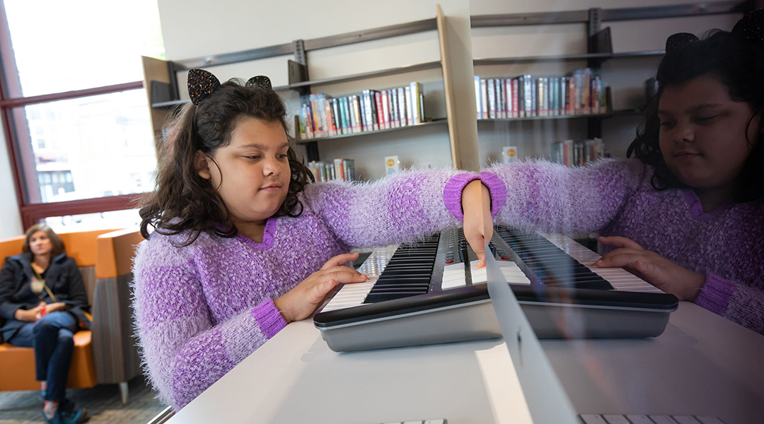 A child plays with an electronic keyboard in the library.