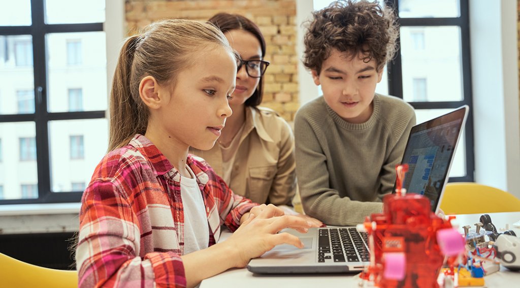 Two children learn programming using laptop during STEM class.