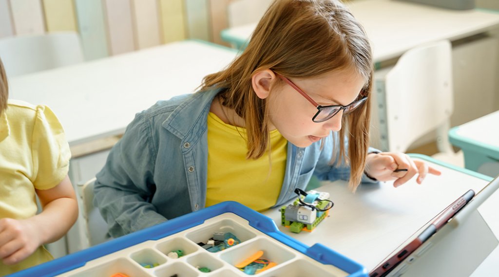 Elementary school children assemble building and robotic parts by instructions.