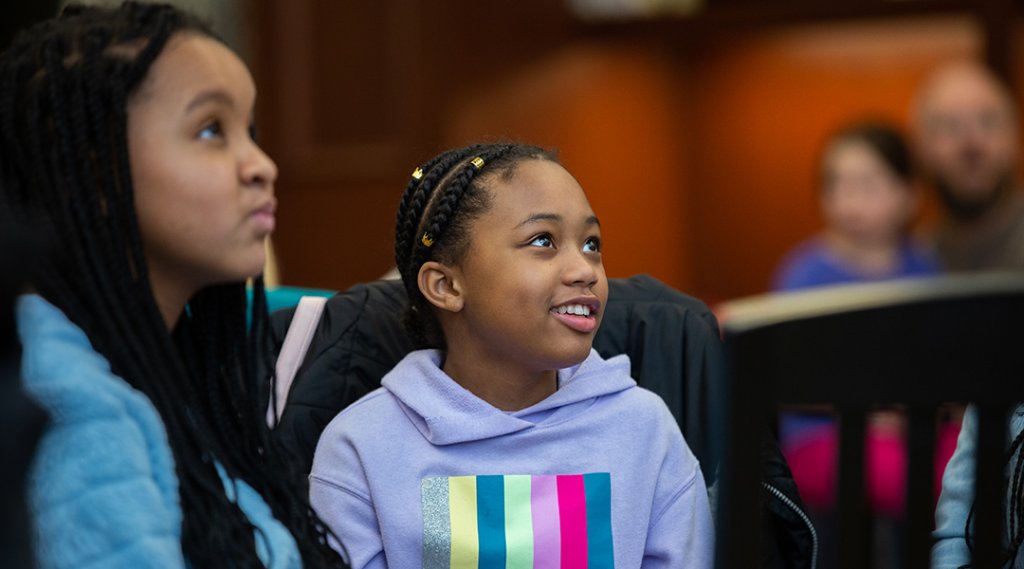 Two children look out of frame during a library program.