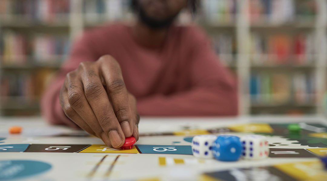 Closeup of a person playing a board game with focus on hand moving game piece.