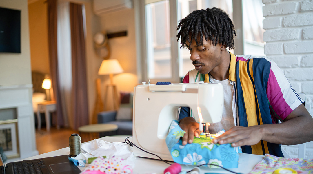 A person guides fabric through a sewing machine.