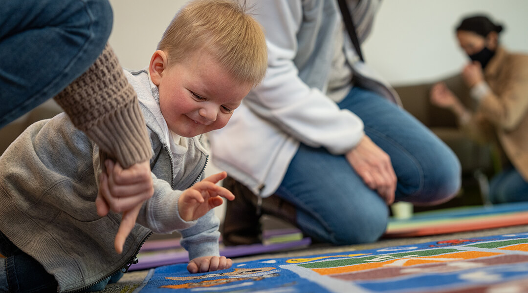 A baby plays on a colorful storytime rug.