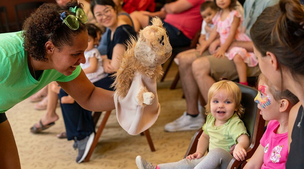 Two young children, about two and four, enjoy a puppet show.