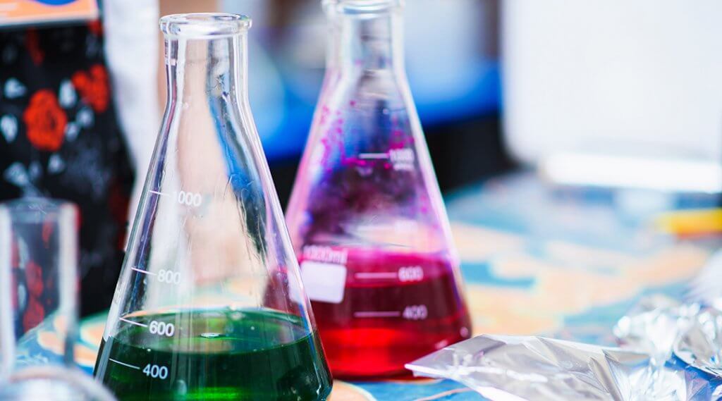 Two chemical flasks on a lab station with different colors of liquid.