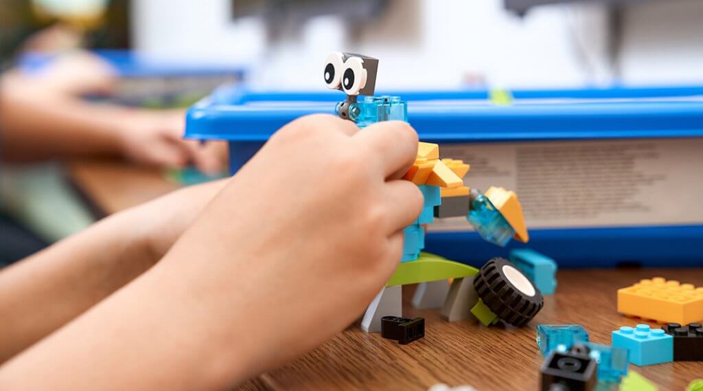 Selective focus of hands using building kit for kids, creating toys.