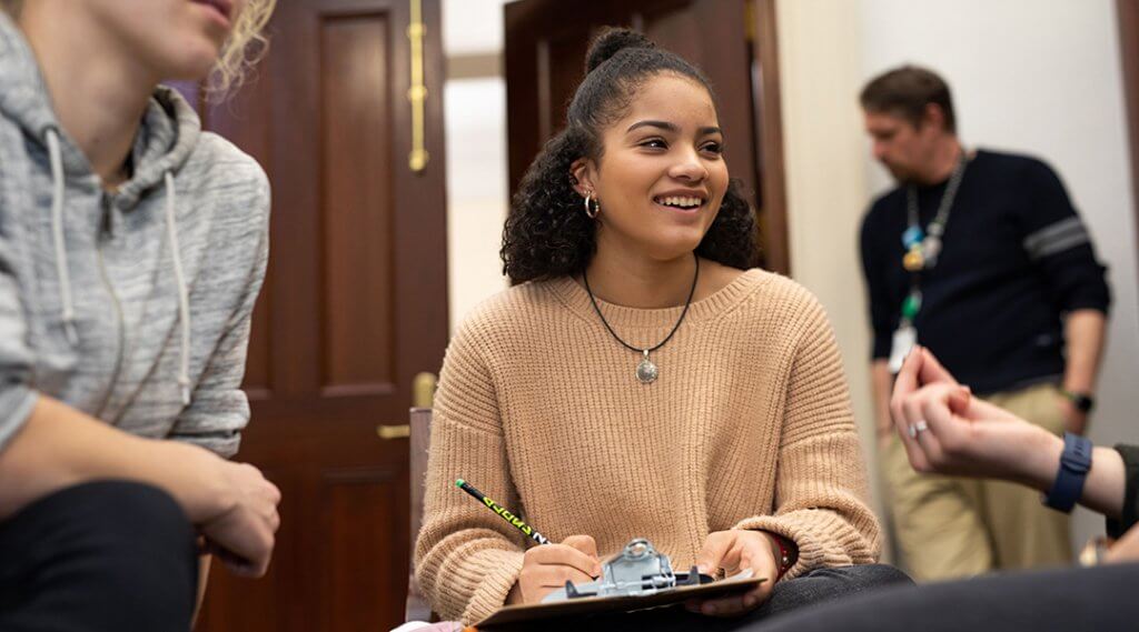 A teenager smiles at their friends during a game of trivia.