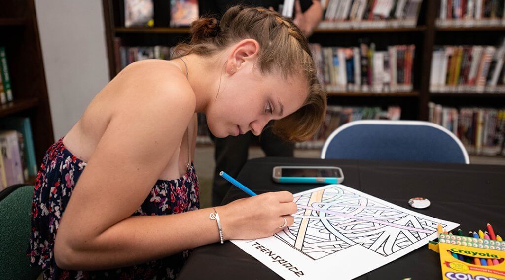 A teenager colors while in the TeenSpace.