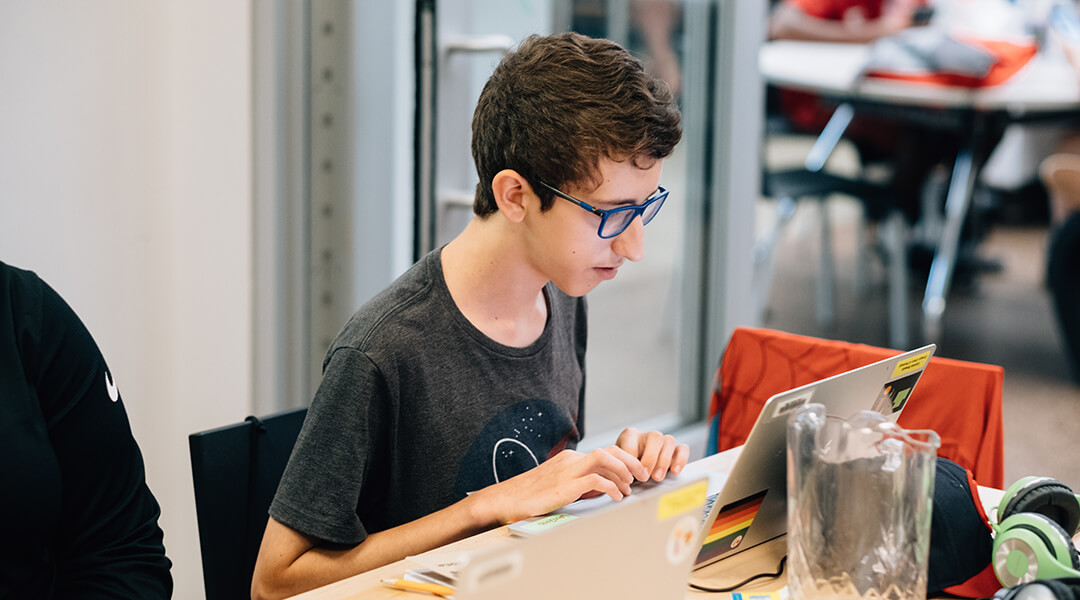 A teenager uses a laptop.