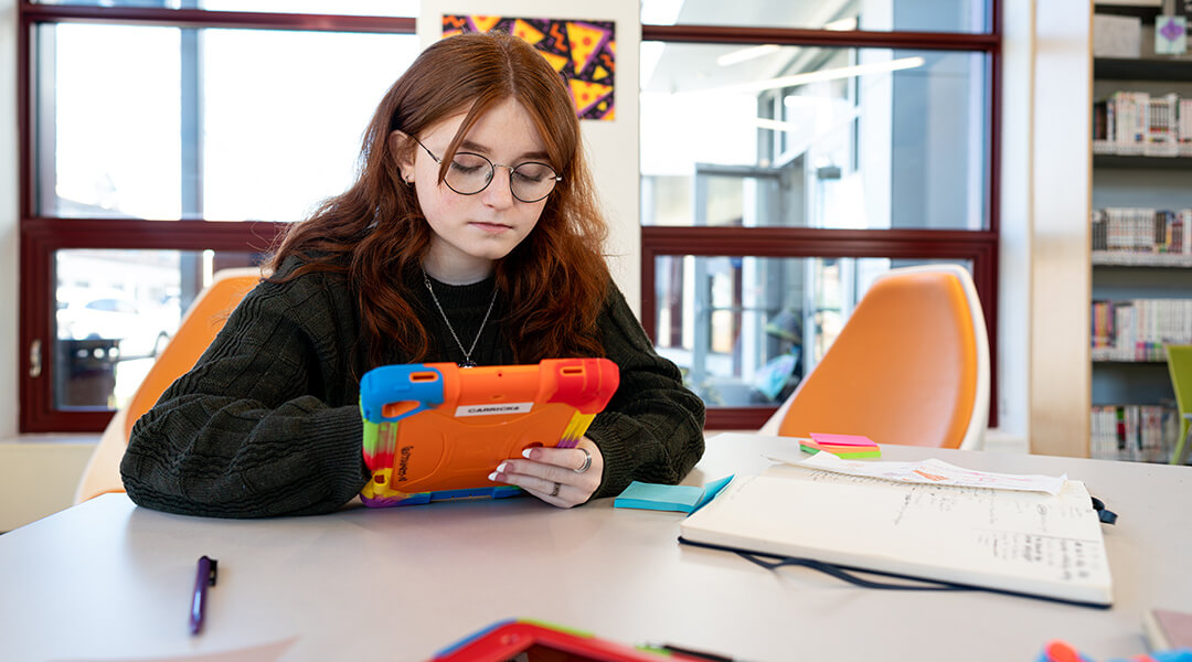 A teenager uses a tablet in the Teenspace.