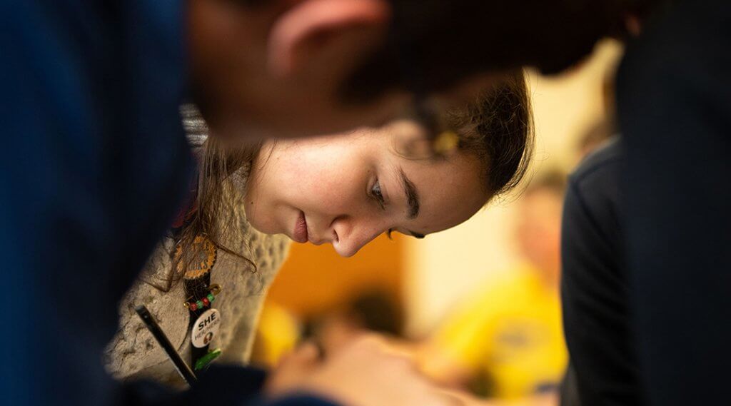 Close-up of a teenager leaning over a table as they write.