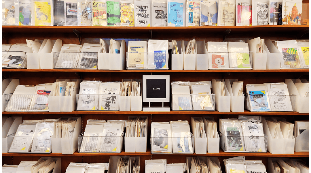 A bookshelf packed with zines in wire bins, magazine holders and faceouts