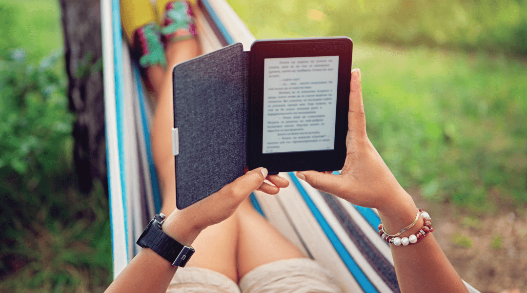 Person relaxing in a colorful hammock while reading from a tablet