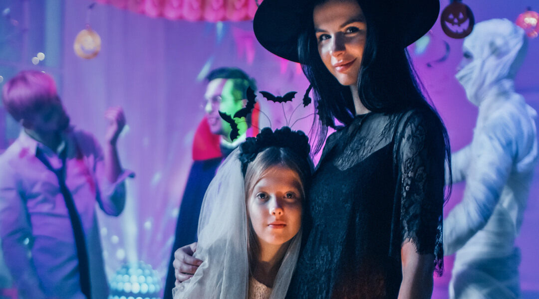 A child and caregiver dressed in costumes pose during a Halloween party.