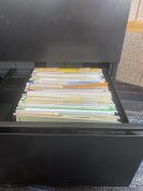 File cabinet open to show paper files in folders.