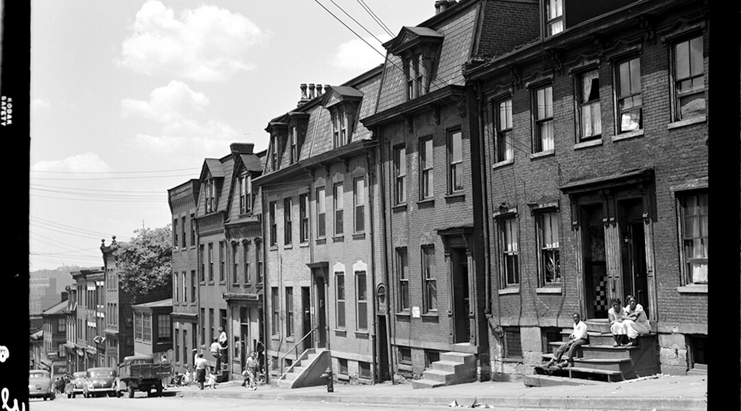 Black and white photo of Historic Pittsburgh featuring a street of rowhouses.