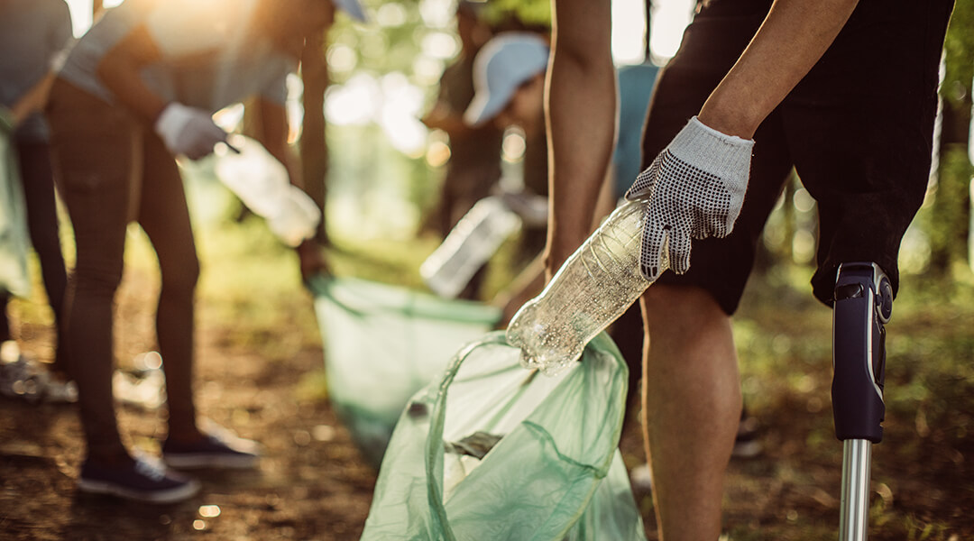 Group of people volunteer and collect trash and recycling in a park.