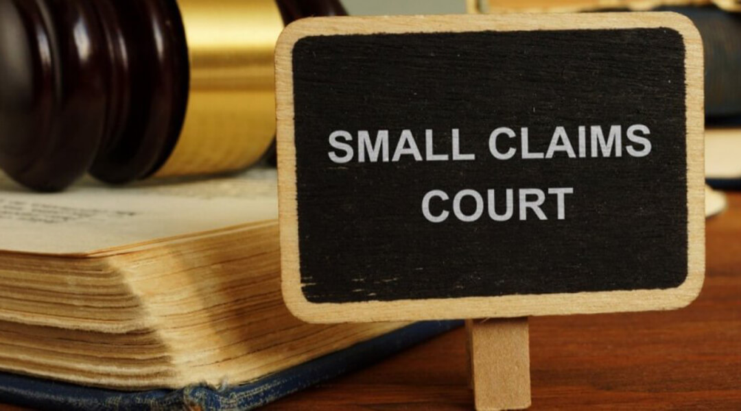 Sign for Small Claims Court in front of law book and gavel.