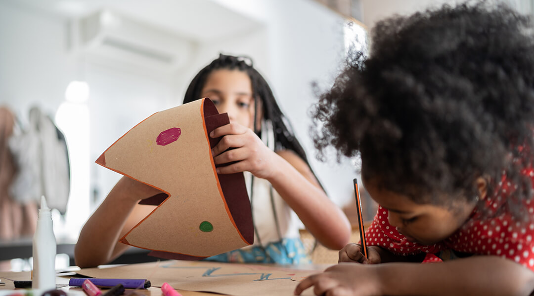 Two siblings preparing a costume, drawing and doing art and craft at home.